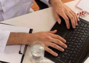 Junger männlicher Arzt mit medizinischer Brille, der ein medizinisches Gewand e mail preis ärzte smartphone schicht hand hilfe 	
psychotherapie